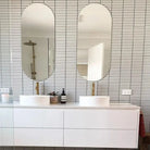 The Sevilla Mosaic Tiles, Finger KitKat design in a Matt White installed in a bathroom. A vanity unit with dual sink basins and two mirrors all wall mounted over the tiles.