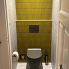 The Sevilla Mosaic Tiles, Original KitKat design in yellow, with a size of 20x145mm. Installed on the wall behind the toilet in a bathroom.